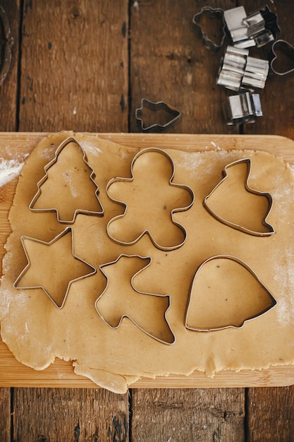 Foto weihnachten lebkuchenplätzchen auf rustikalen tisch machen lebkuchenteig mit festlichen metallschneidern