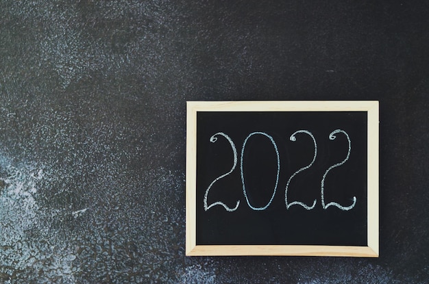 Weihnachten Neujahr flach lag auf schwarzem Hintergrund Zahlen 2022 auf einer Schreibtafel Nahaufnahme Flatlay