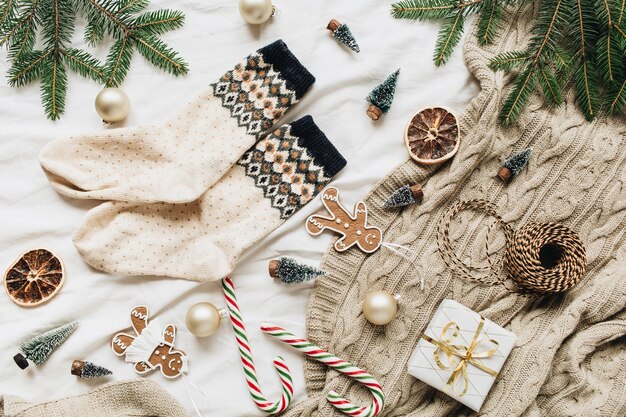 Weihnachten neujahr komposition. wollsocken, geschenkbox, tannenzweige, weihnachtskugeln, ingwerplätzchen, stockbonbons, gestricktes plaid, dekorationen