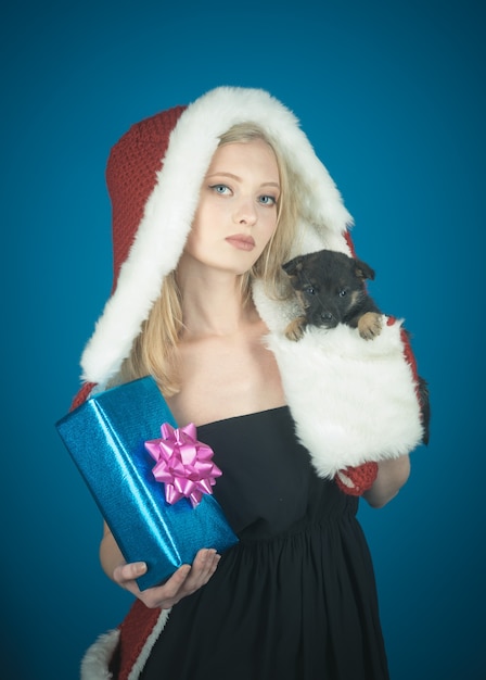 Weihnachten Neujahr Winterurlaub und Menschen Konzept Mädchen halten süßen Welpen und blaues Geschenk in Händen