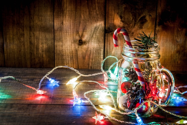 Weihnachten, Neujahrskonzept. Mason Jar mit Weihnachtsdekorationen, Tannenzapfen, künstlichem Schnee, Zuckerstange und Tannenzweig.