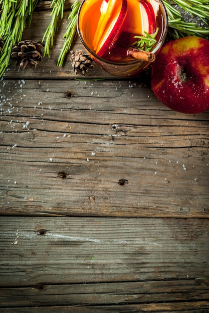 Foto weihnachten, thanksgiving-drinks. herbst, wintercocktailgrog, heiße sangria, glühwein - apfel, rosmarin, zimt, anis. auf altem rustikalem holztisch. mit zapfen, rosmarin. kopieren sie die draufsicht des raumes