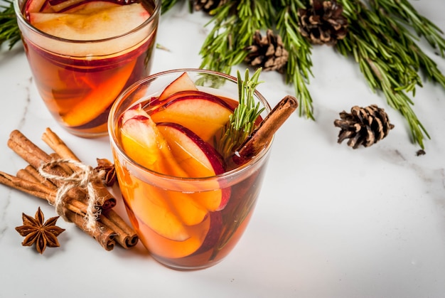 Weihnachten, Thanksgiving-Drinks. Herbst, Wintercocktailgrog, heiße Sangria, Glühwein - Apfel, Rosmarin, Zimt, Anis. Auf weißer Marmortabelle. Mit Zapfen, Rosmarin. Kopieren Sie Platz