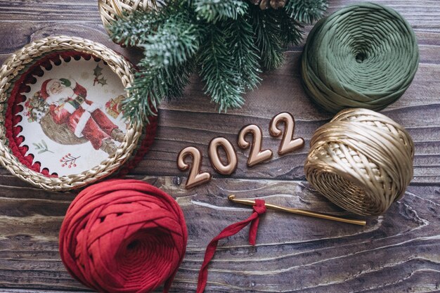 Weihnachten und Neujahr 2022 Grußkarte Kugeln Garn Häkelnadel und Strickkorb Holztisch