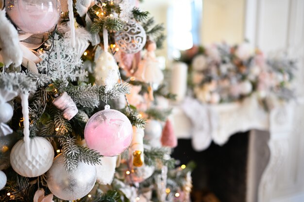 Weihnachten verzierte Baum in den weichen rosa Farben vor dem hintergrund des weißen klassischen Kamins mit Weihnachtsdekorationen.