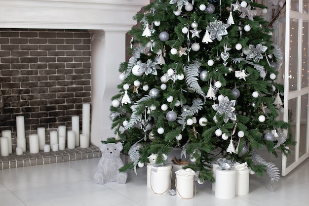 Weihnachten! verziertes wohnzimmer mit kamin mit schönem weihnachtsbaum und bällen. weihnachtsgeschenkboxen auf boden nahe tannenbaum im raum.