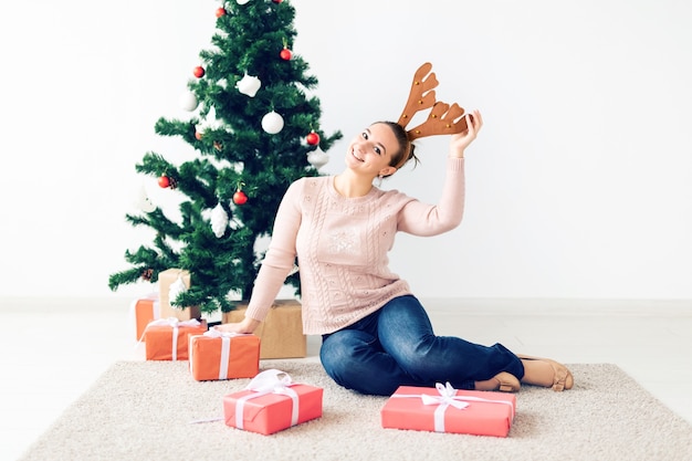 Weihnachten, Weihnachten, Winter, Glückskonzept - Mädchen öffnet ein Geschenk vor dem Hintergrund des Weihnachtsbaums. Glückliche junge Frau, die Weihnachten feiert