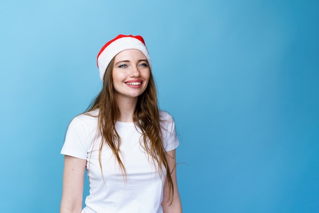 Weihnachten weihnachtsmütze isoliert frau porträt lächelnd glückliches mädchen auf blauem hintergrund im weißen t...