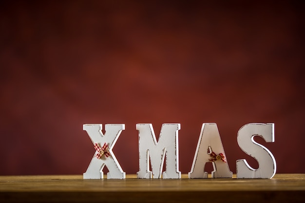 Foto weihnachten. weihnachtswort aus holzbuchstaben auf einem holztisch. weihnachtskugeln tannenzapfen stern tannenzweig als dekoration