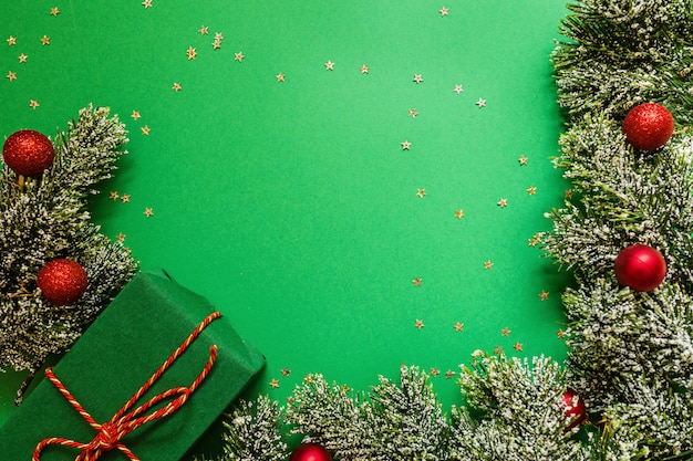 Weihnachten wickelte Geschenkbox und Baumaste auf grünem Hintergrund mit Konfettis ein