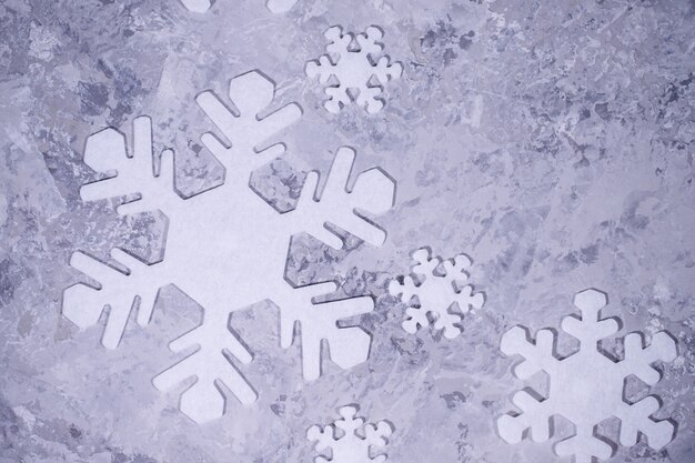 Foto weihnachten, winter, neujahrskonzept. grauer hintergrund mit weißen schneeflocken. flachgelegt, draufsicht