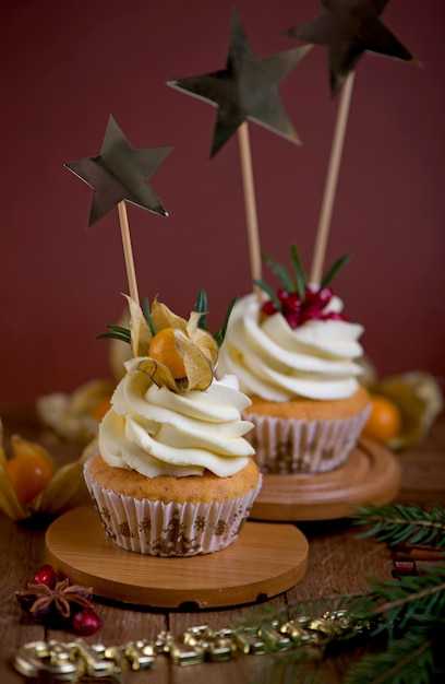 Weihnachts-Cupcakes mit Vanille-Zuckerguss, Preiselbeeren und Rosmarin auf Holzhintergrund. Selektiver Fokus