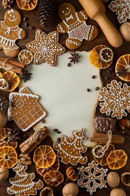 Weihnachts-Ingwer-Plätzchen Stilleben auf einem Tisch mit einem Nudelholz Nelken, getrockneten Zitrusfrüchten, Pinienkernen und Zapfen, Zimt, Walnuss und Kraftpapier