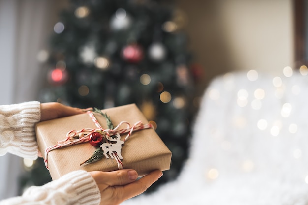 Weihnachts-Öko-Geschenk in Frauenhänden Glühendes Schneebokeh