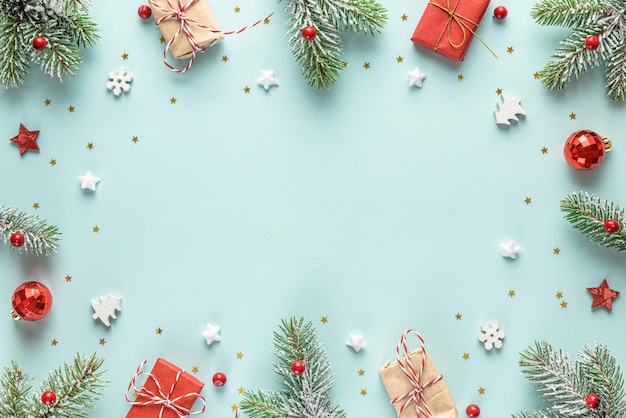 Weihnachts- oder Frohes neues Jahr-Rahmen aus Tannenzweigen, Weihnachtsschmuck, Geschenkboxen auf blauem Hintergrund
