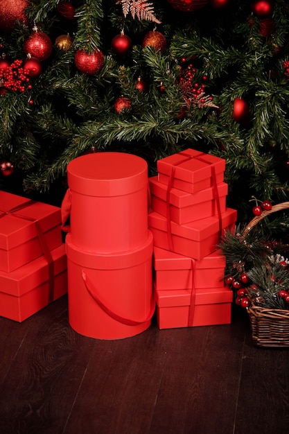Weihnachts- oder Neujahrsfeierhintergrund der gegenwärtigen roten Geschenkboxen und der Tannenzweige. Neujahrsgeschenke stehen unter dem Weihnachtsbaum mit Spielzeug. Hintergrund für die Website. Kopieren Sie Platz, Textplatz