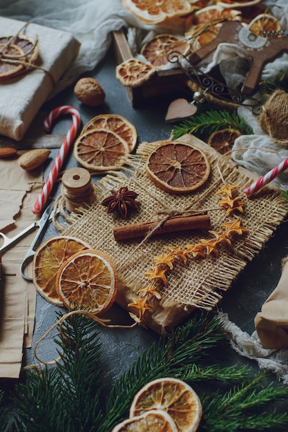 Weihnachts- oder Neujahrskomposition mit handgefertigten Geschenken trocknen Orangen Zimttannenbaum auf dunklem Steintisch