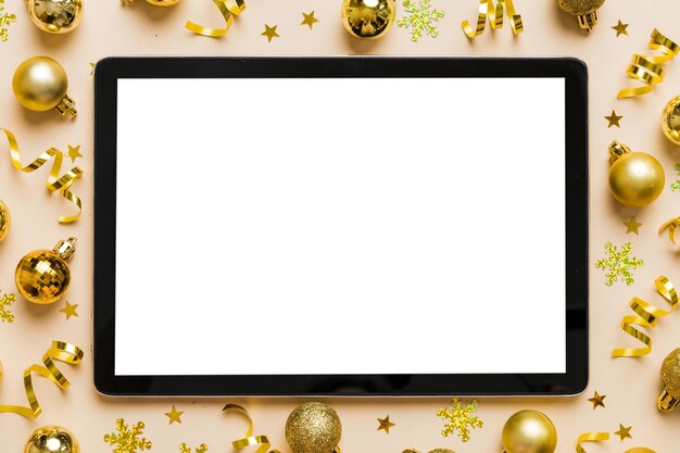 Foto weihnachts-online-shopping von zu hause aus tablet-pc mit leerer weißer anzeige top-view tablet mit kopierraum auf farbigen hintergrund mit weihnachtendekorationen bälle winterferien verkaufs-hintergrund