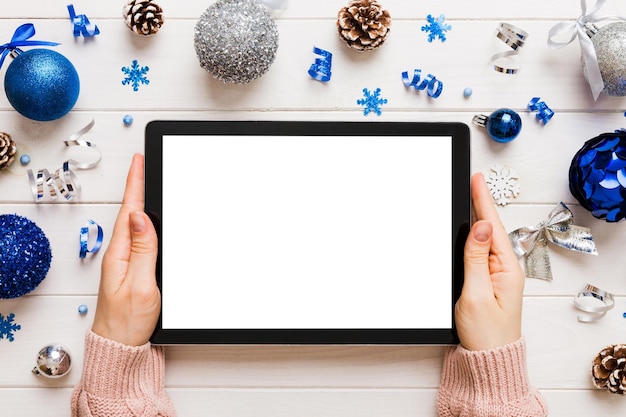 Weihnachts-Online-Shopping von zu Hause aus weibliche Hände halten Tablet-PC mit leerem weißen Display Top-View weibliche Hand hält Tablet mit leerem Bildschirm Weihnachtsbaum und Geschenke auf dem Hintergrund