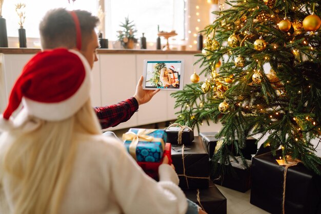 Weihnachts-Online-Urlaub Junges Paar mit Videoanruf mit Familie oder Freunden Virtuelles Treffen