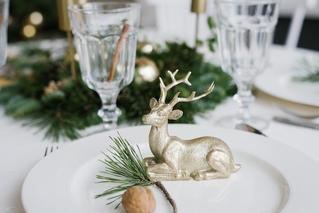 Weihnachts-Souvenirhirsch auf einem weißen Teller mit einem Kiefernzweig und einer Walnuss.