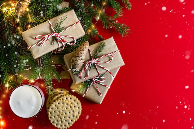 Weihnachts- und feiertagskonzept flache lage mit kopierraum roter hintergrund leckereien für den weihnachtsmann milch und kekse tannenzweige