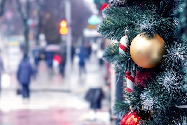 Weihnachts- und Neujahrsbaumschmuck auf einem Baumzweig auf einer Stadtstraße auf verschwommenem Hintergrund am Vorabend des Feiertags