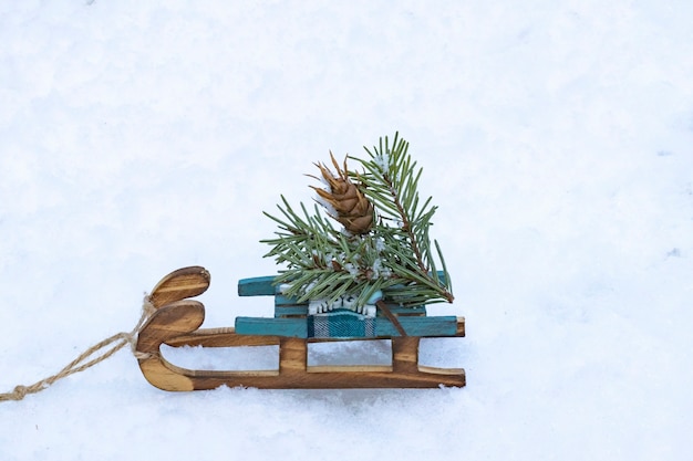 Weihnachts- und Neujahrsbaumspielzeug. Kleiner Holzschlitten mit einem Weihnachtsbaum auf dem Schnee im Winter