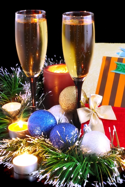 Weihnachts- und Neujahrsdekoration - Kugeln, Lametta, Kerzen und Gläser Champagner. Auf schwarzem Hintergrund.