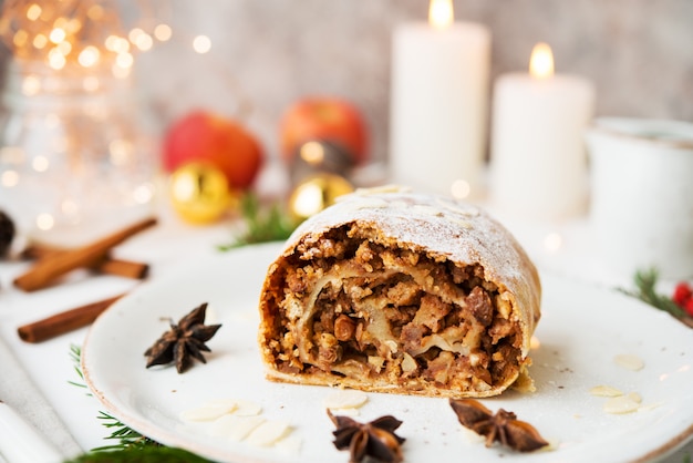 Weihnachts- und Neujahrsdessert. Apfelkuchen in festlicher Dekoration, mit Girlanden und Weihnachtsspielzeug.