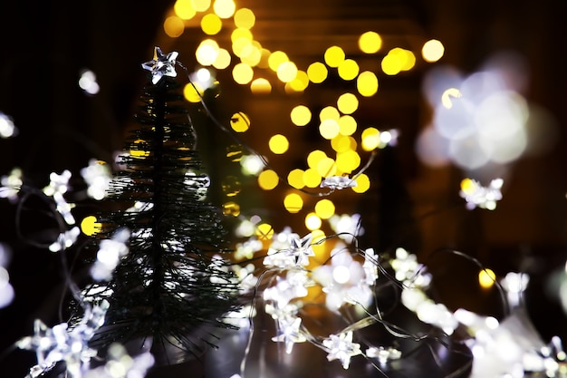 Weihnachts- und Neujahrsfeiertagshintergrund mit Kopienraum. Winterurlaubshintergrund mit gefrorener Tanne, Glitzerlichtern, Bokeh.