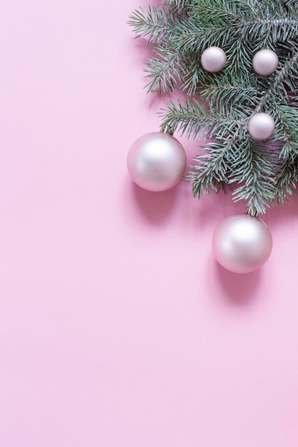 Weihnachts- und Neujahrsfestkomposition mit Tannenzweigen und sanften rosa Weihnachtskugeln auf rosa Hintergrund