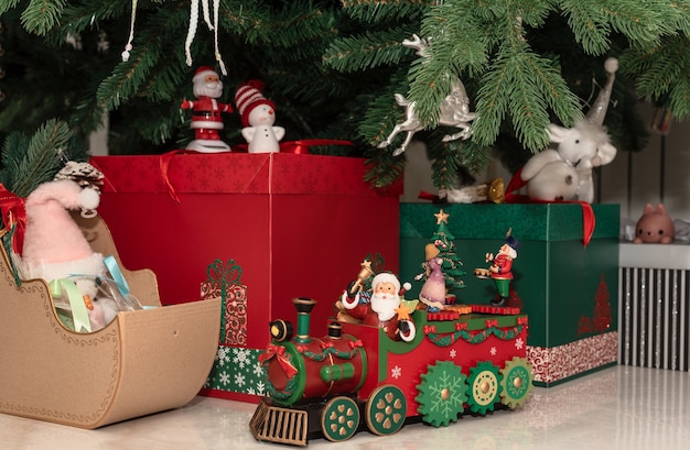 Weihnachts- und Neujahrsgeschenkboxen und schöne Dekorationen stehen auf dem Boden unter dem Weihnachtsbaum.