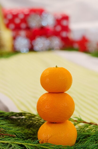 Weihnachts- und Neujahrshintergrund mit Tannenzweigen, Dekorationen und orangefarbenen frischen Mandarinen. Eben