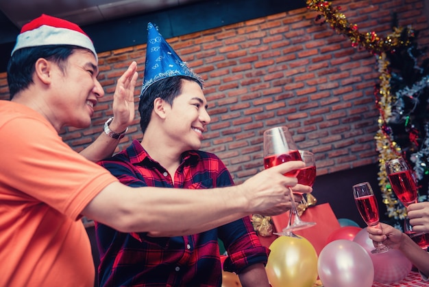 Weihnachts- und Silvesterparty mit Freunden. Homosexuelles Paar trinkt Rotwein in der Urlaubsnacht.