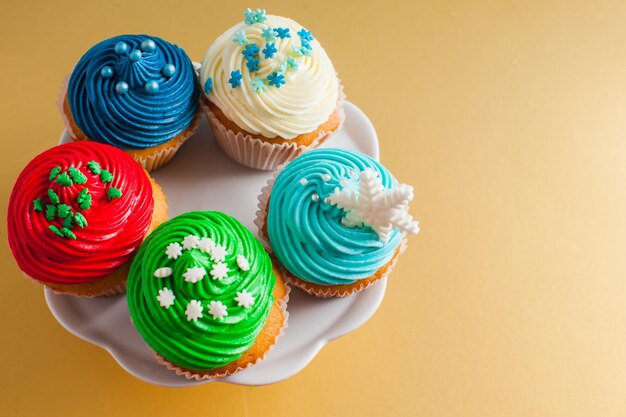 Weihnachts- und Wintercupcakes auf dem Cakestand und dem Goldhintergrund