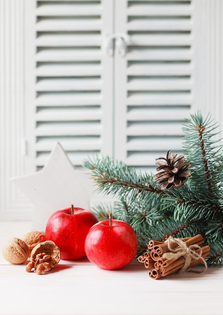 Weihnachts- und Winterzusammensetzung mit Tannenzweigen, Apfel, Walnüssen und Zimt.