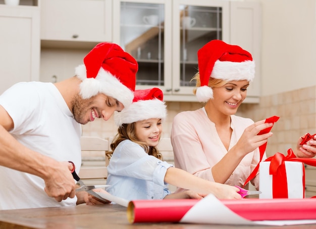 Weihnachts-, Weihnachts-, Winter-, Familien-, Glücks- und Menschenkonzept - lächelnde Familie in Weihnachtsmannmützen mit Geschenkbox