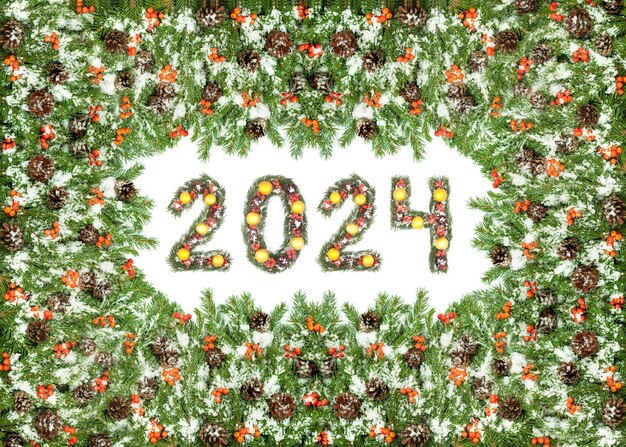 Foto weihnachtsabend-hintergrund und 2024 nummer gemacht von weihnachtenbaumzweigen isoliert auf weißem hintergrund