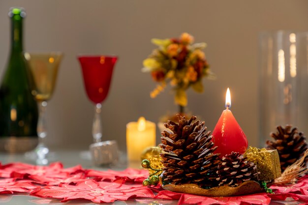 Weihnachtsarrangement mit Tannenzapfen und brennenden Kerzen und unscharfem Hintergrund