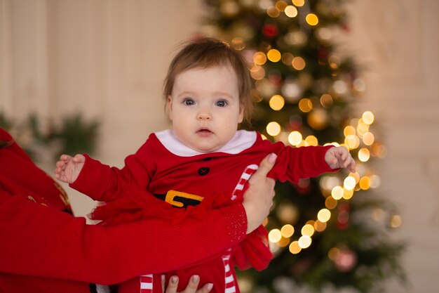 Weihnachtsbaby im Weihnachtsmannkostüm nahe Weihnachtsbaum. Frohe Weihnachten und ein glückliches Neues Jahr.