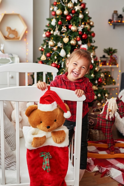 Weihnachtsbaby. Kleines lächelndes Mädchen im weißen Bett im Kinderzimmer