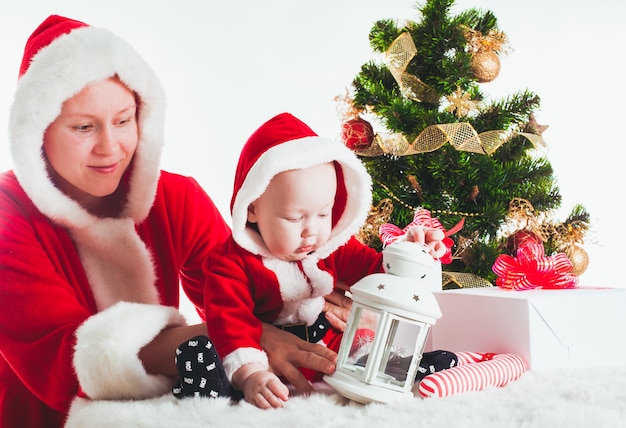 Weihnachtsbaby und Mama unter dem Tannenbaum isoliert