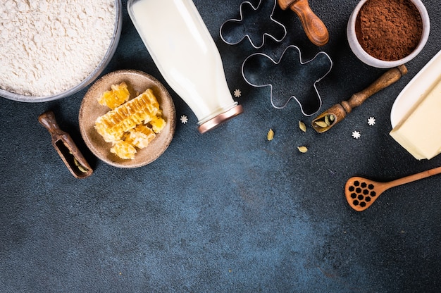 Weihnachtsbacken Hintergrund. Zutaten zum Kochen von Weihnachtsbäckerei auf dunklem Hintergrund. Draufsicht mit Kopienraum. Lebkuchen Kekse. Ingwerplätzchen backen. Roher Teig für Kekse