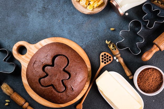 Weihnachtsbacken Hintergrund. Zutaten zum Kochen von Weihnachtsbäckerei auf dunklem Hintergrund. Draufsicht mit Kopienraum. Lebkuchen Kekse. Ingwerplätzchen backen. Roher Teig für Kekse