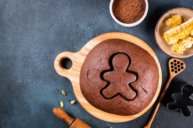 Weihnachtsbacken Hintergrund. Zutaten zum Kochen von Weihnachtsbäckerei auf dunklem Hintergrund. Draufsicht mit Kopienraum. Lebkuchen Kekse. Ingwerplätzchen backen. Roher Teig für Kekse