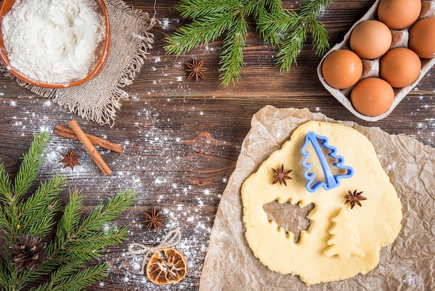 Weihnachtsbacken von Ingwerplätzchen auf dunklem hölzernem Hintergrund mit Tannenzweigen.