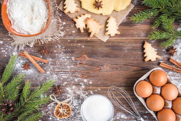 Weihnachtsbacken von Ingwerplätzchen auf dunklem hölzernem Hintergrund mit Tannenzweigen.