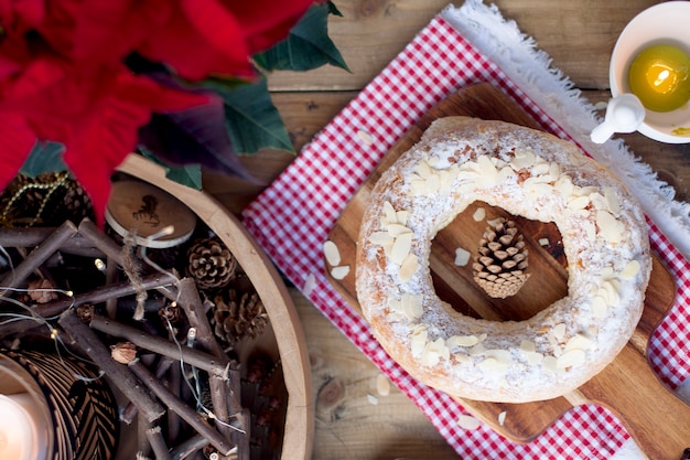 Weihnachtsbackwaren auf einer Tabelle und einer Blume mit roten Blättern, Kerzen