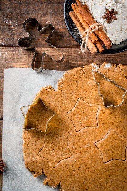 Weihnachtsbäckerei. Ingwertig für Lebkuchen, Lebkuchenmänner, Sterne, Weihnachtsbäume, Nudelholz, Gewürze (Zimt und Anis), Mehl. Auf dem Hauptküchenholztisch. Kopieren Sie die Draufsicht des Raumes